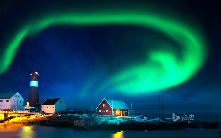 Winter seashore, northern lights over lighthouse